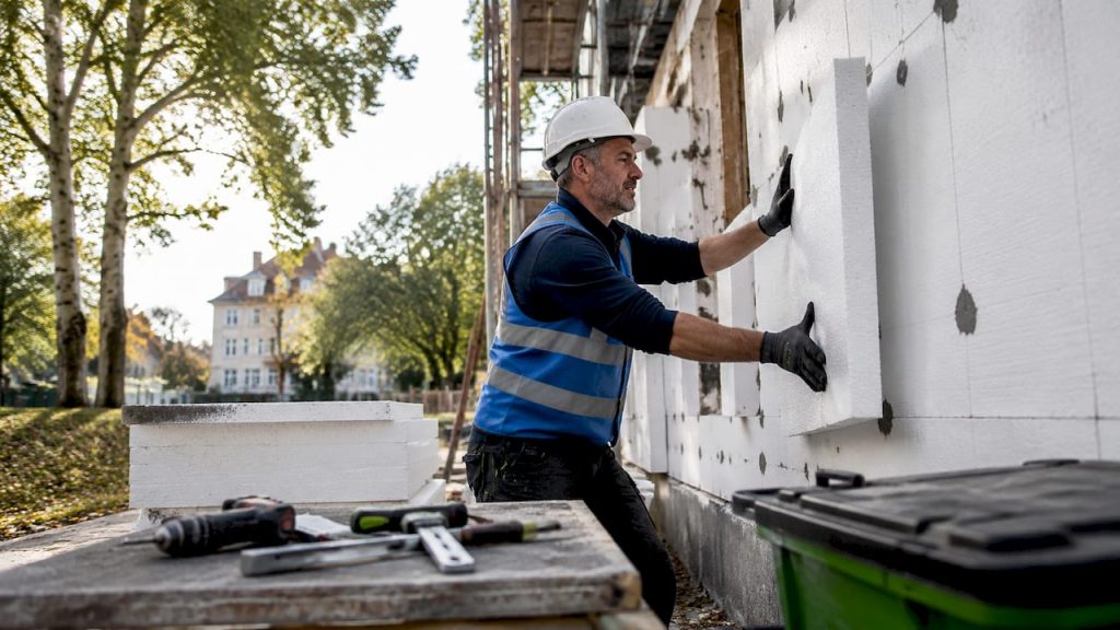 Profissional a aplicar isolamento térmico na fachada do edifício
